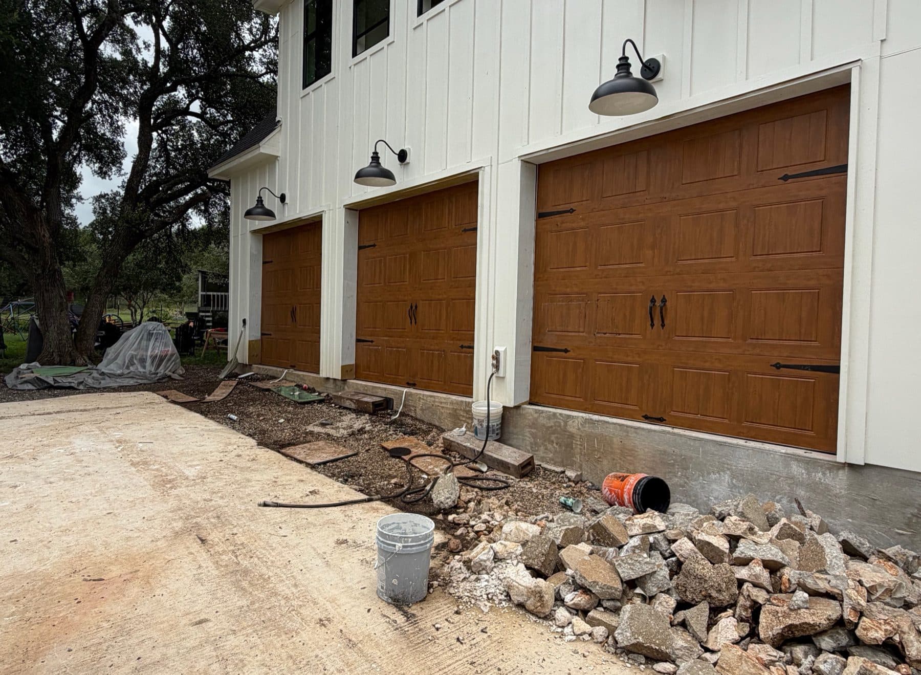 Three-bay modern farmhouse garage with oak carriage doors and black gooseneck lights