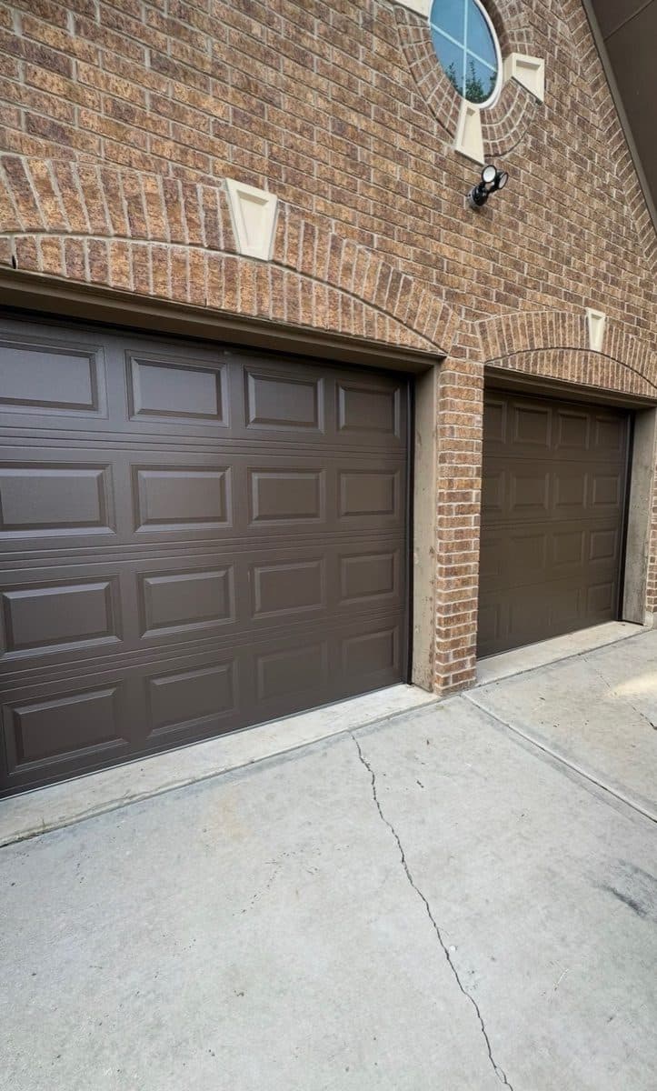 Brown raised-panel garage doors on a tan brick home